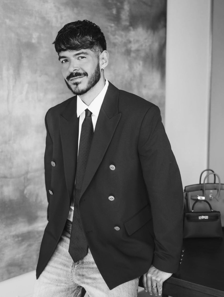 Portrait of Nick Collins wearing a double breasted blazer and tie with jeans.